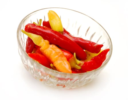 red and yellow hot peppers in glass bowl isolated over white