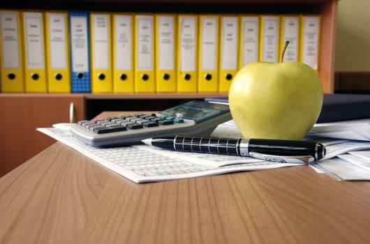 office desk papers, calculator, pen and apple