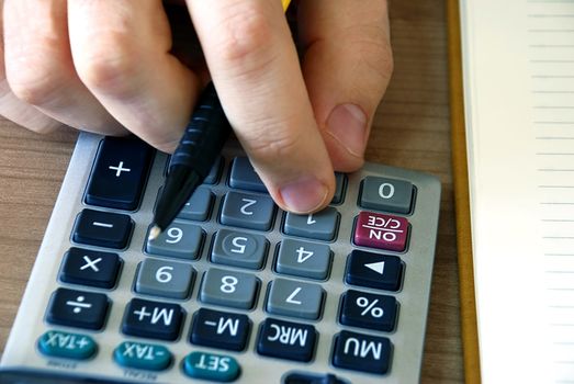 man fingers over gray calculator buttons closeup