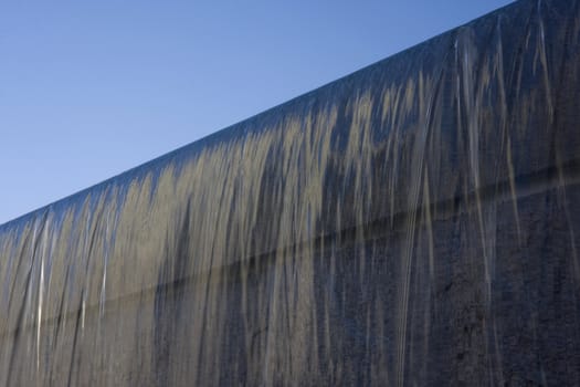 fountain water flowing on granite wall under blue sky