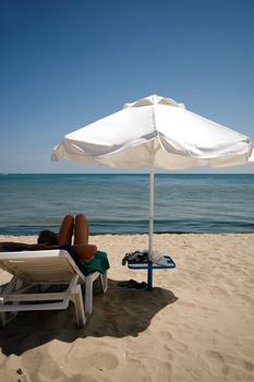 Man, umbrella and sunbed. Taken on a sunny day.