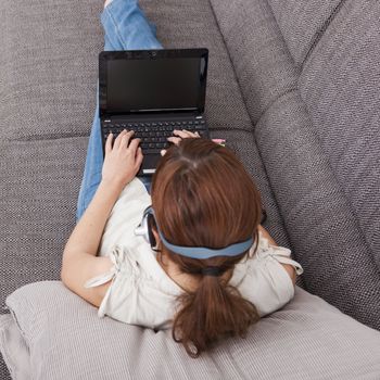 Beautiful young woman at home with a laptop and speaking over the internet with  headphones