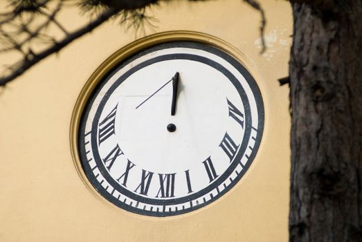 a sun dial on a house with a tree as a border