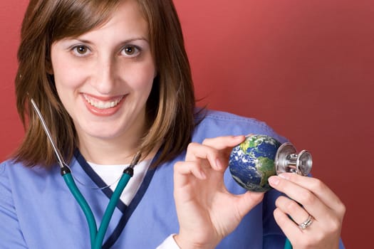 A young nurse holds a stethoscope to the earth.  This conceptual image works great for the going green movement.