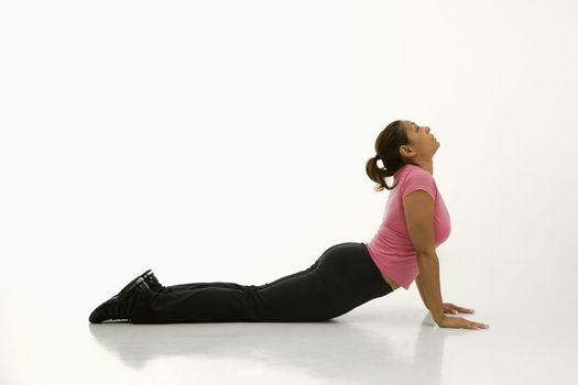Side view of mid adult multiethnic woman wearing exercise clothing holding cobra yoga pose.