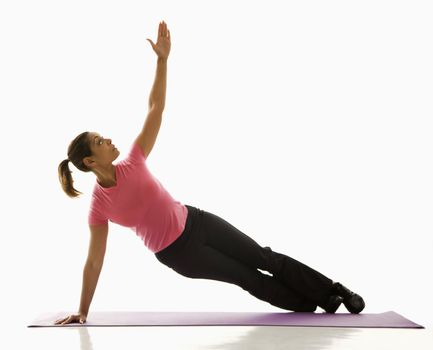 Mid adult multiethnic woman wearing exercise clothing holding yoga pose and stretching.