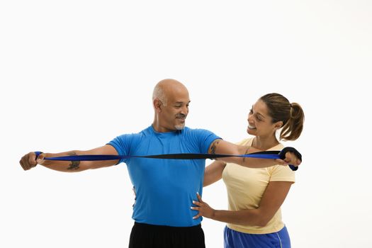Mid adult multiethnic woman assisting mid adult multiethnic man with stretching band.