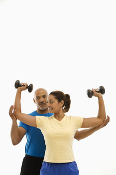 Smiling mid adult multiethnic man assisting mid adult multiethnic woman with dumbbells.
