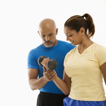 Mid adult multiethnic man assisting smiling mid adult multiethnic woman with dumbbells.