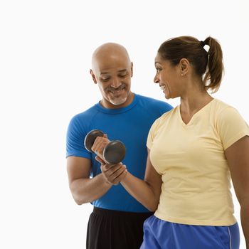 Smiling mid adult multiethnic man assisting mid adult multiethnic woman with dumbbells.