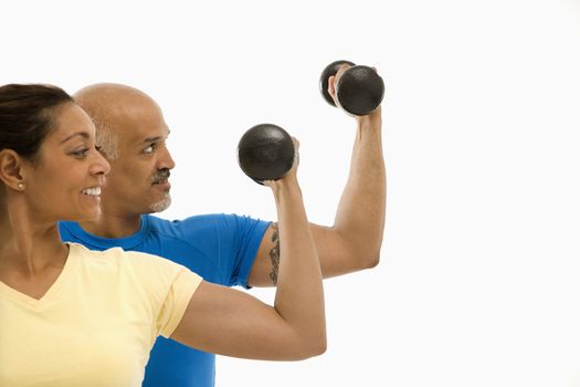 Smiling mid adult multiethnic man and woman exercising with dumbbells doing bicep curls.