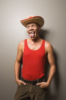 Portrait of a Mid-adult Caucasian male wearing straw hat sticking out tongue.