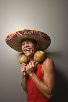 Portrait of a Mid-adult Caucasian male wearing sombrero holding maracas.