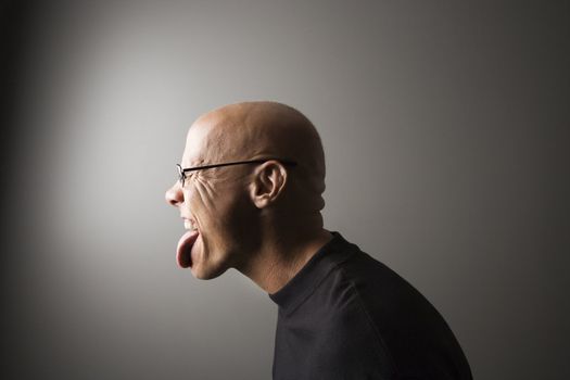 Profile portrait of mid-adult Caucasian male sticking out tongue.