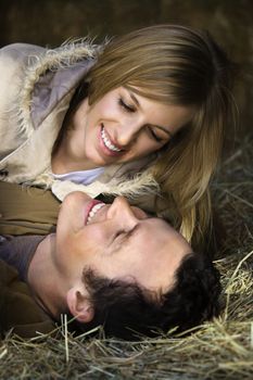 Young adult Caucasian couple lying in hay.