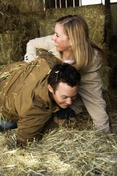 Young adult Caucasian couple playing in hay.