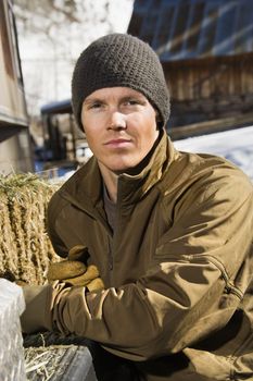 Young Caucasian man wearing hat outdoors in rural country looking at viewer.