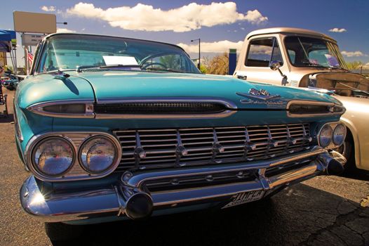 A baby blue 1959 Chevrolet Impala hotrod car sits idle at a car show