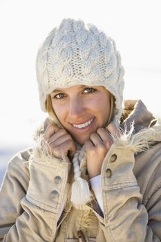 Young adult Caucasian woman in winter attire holding collar and smiling at viewer.