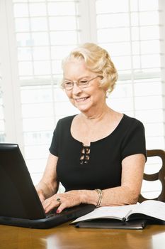 Mature Caucasian woman using laptop in living room.