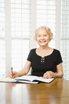 Mature Caucasian woman writing in calendar.