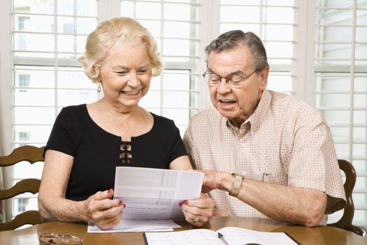 Mature Caucasian couple looking at their bills.