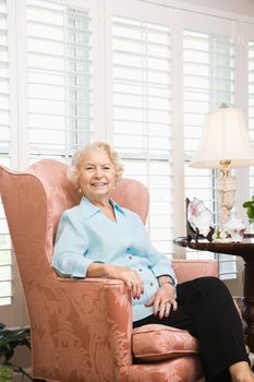 Mature Caucasian woman sitting in chair looking at viewer.