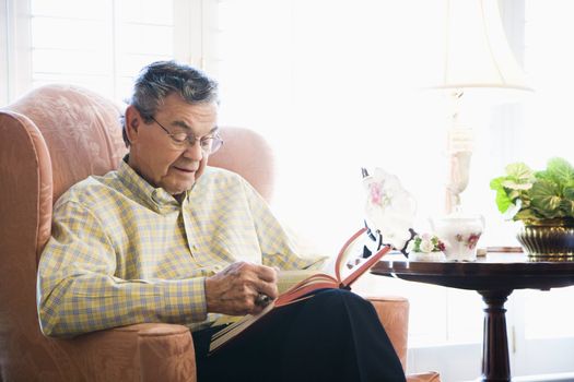 Mature Caucasian man sitting in chair reading a book.