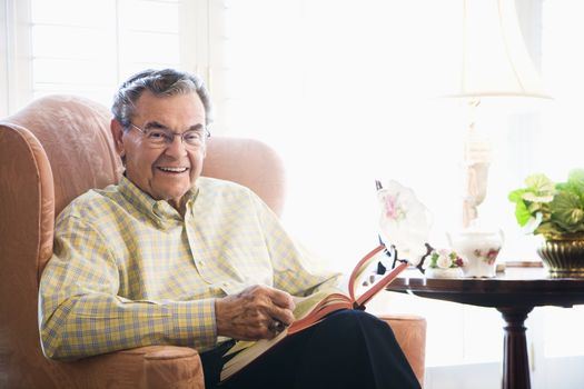 Mature Caucasian man sitting in chair reading a book.