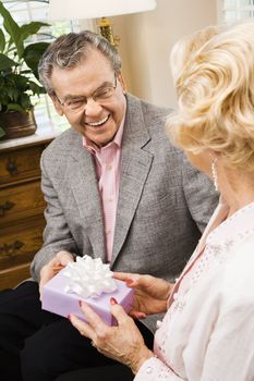 Mature Caucasian man giving present to mature Caucasian woman.