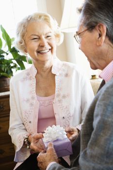 Mature Caucasian man giving present to mature Caucasian woman.