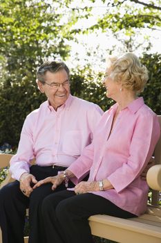 Mature Caucasian couple sitting together on bench.