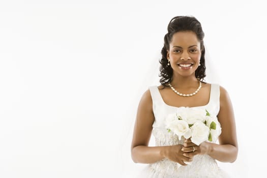 Mid-adult African-American bride holding bouquet on white background.