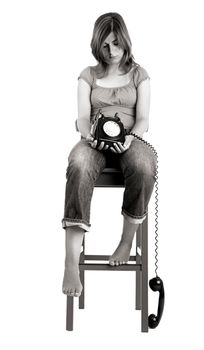 Sad woman seated in a chair with a the phone on is hands