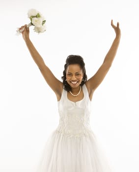 Portrait of a mid-adult African-American bride holding bouquet with arms raised.