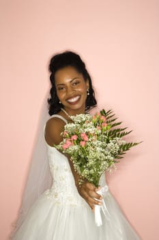 Portrait of a mid-adult African-American bride on pink background.