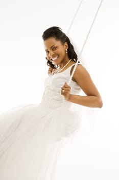 Mid-adult African-American bride swinging with white background.