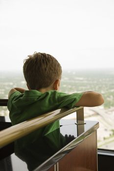 Young Caucasian boy leaning on railing at observation deck at Tower of the Americas in San Antonio, Texas.