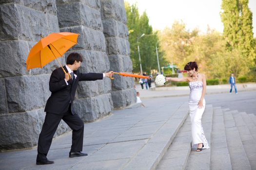 playing bride and groom with orange umbrellas 