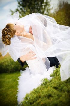 bride and groom kissing in the park