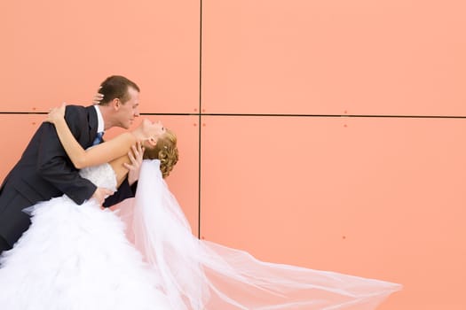 kiss of bride and groom near the wall 