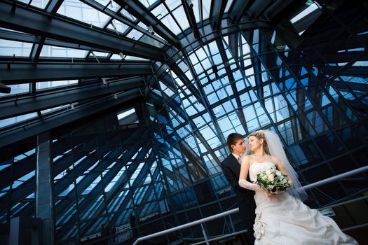 bride and groom under the glass ceiling 