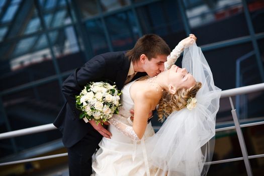 groom and bride kiss under the glass ceiling
