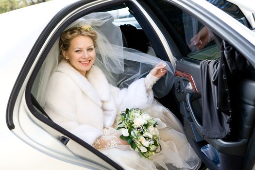 happy bride with flower bouquet siting in the car