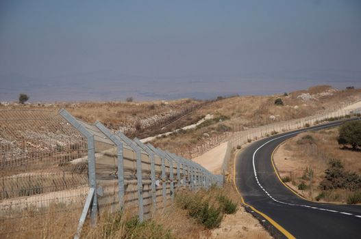 A fence topped with barbed wire separates Israel from Lebanon .