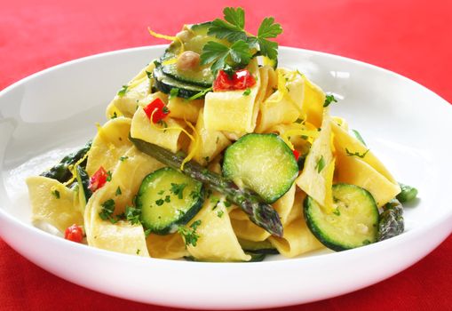Fresh pappardelle with zucchini, asparagus, peppers, and a creamy sauce.  Delicious wide ribbon pasta, garnished with parsley and lemon zest.