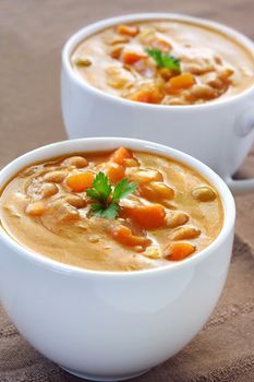 Cups of hearty vegetable soup.  Focus on front cup.