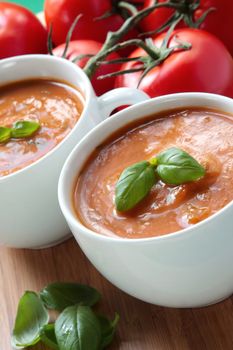 Cups of tomato soup with basil leaves.