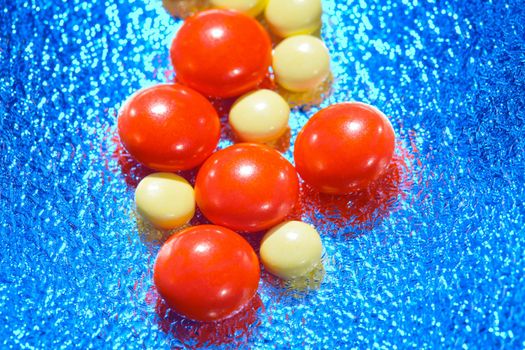 medicine, red and yellow tablet on blue background, close-up