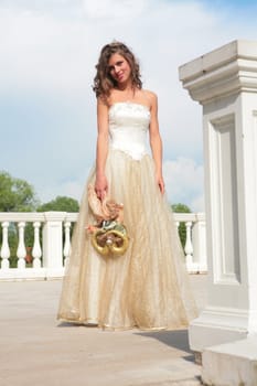 smiling girl in white-golden gown and with doll in hand